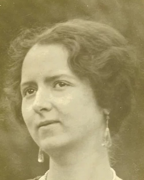Portrait photograph of a young European woman with dark wavy hair and drop earrings